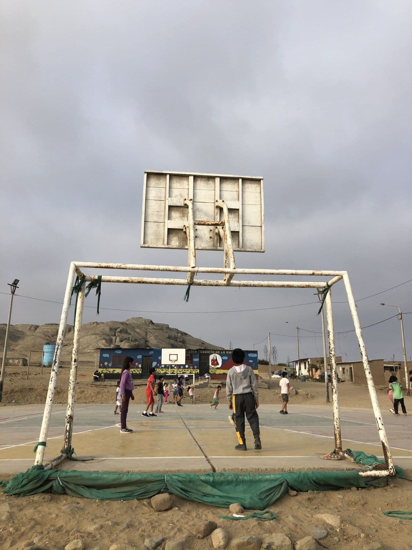 Children playing on the sports court in Cerrito de la Virgen, with desert hills behind