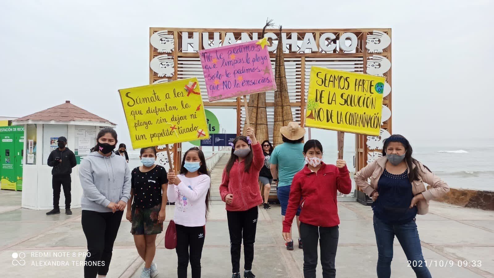 Girls marching through Huanchaco carrying hand-made placards
