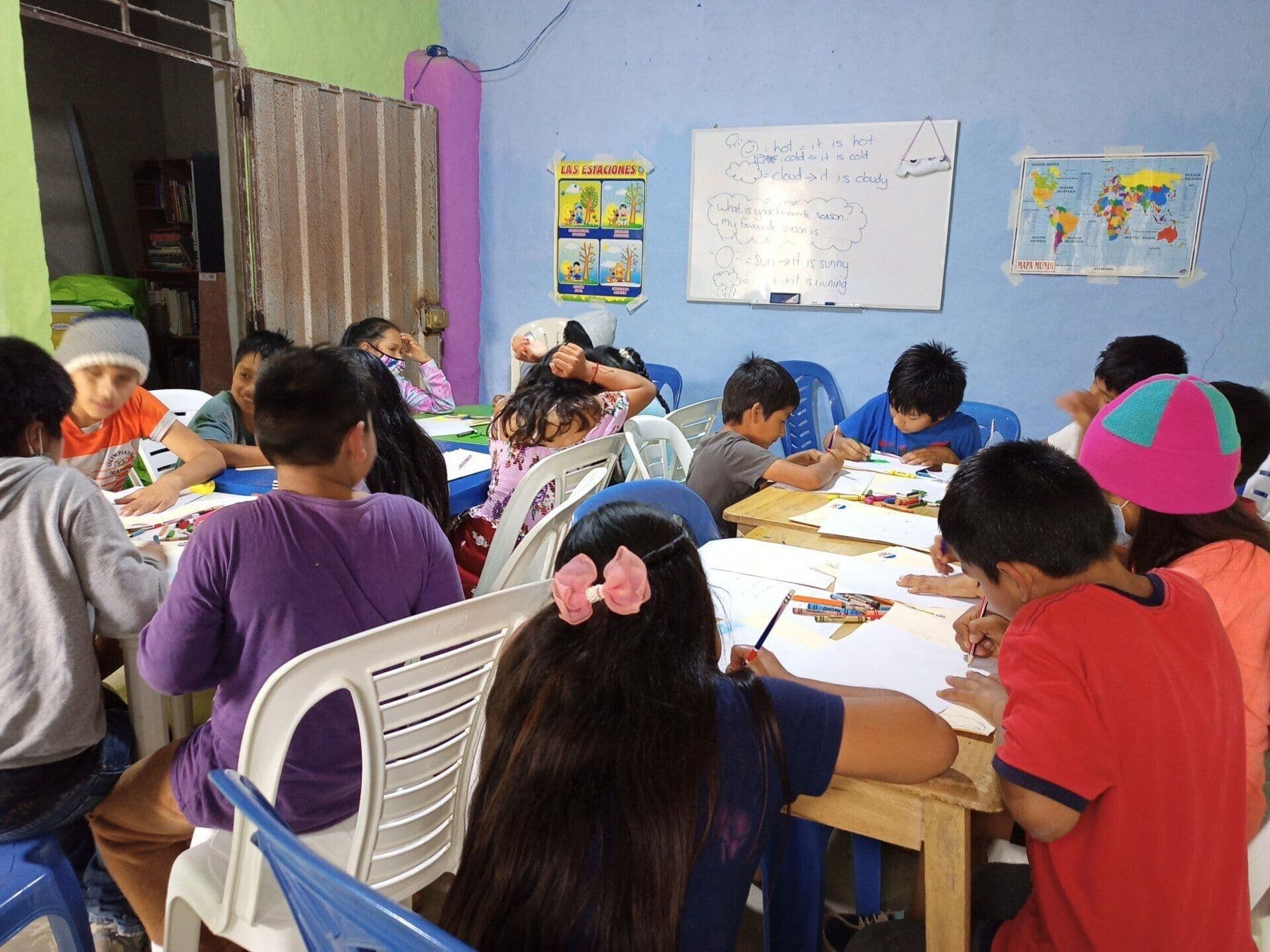 Children writing and drawing at tables during a lesson