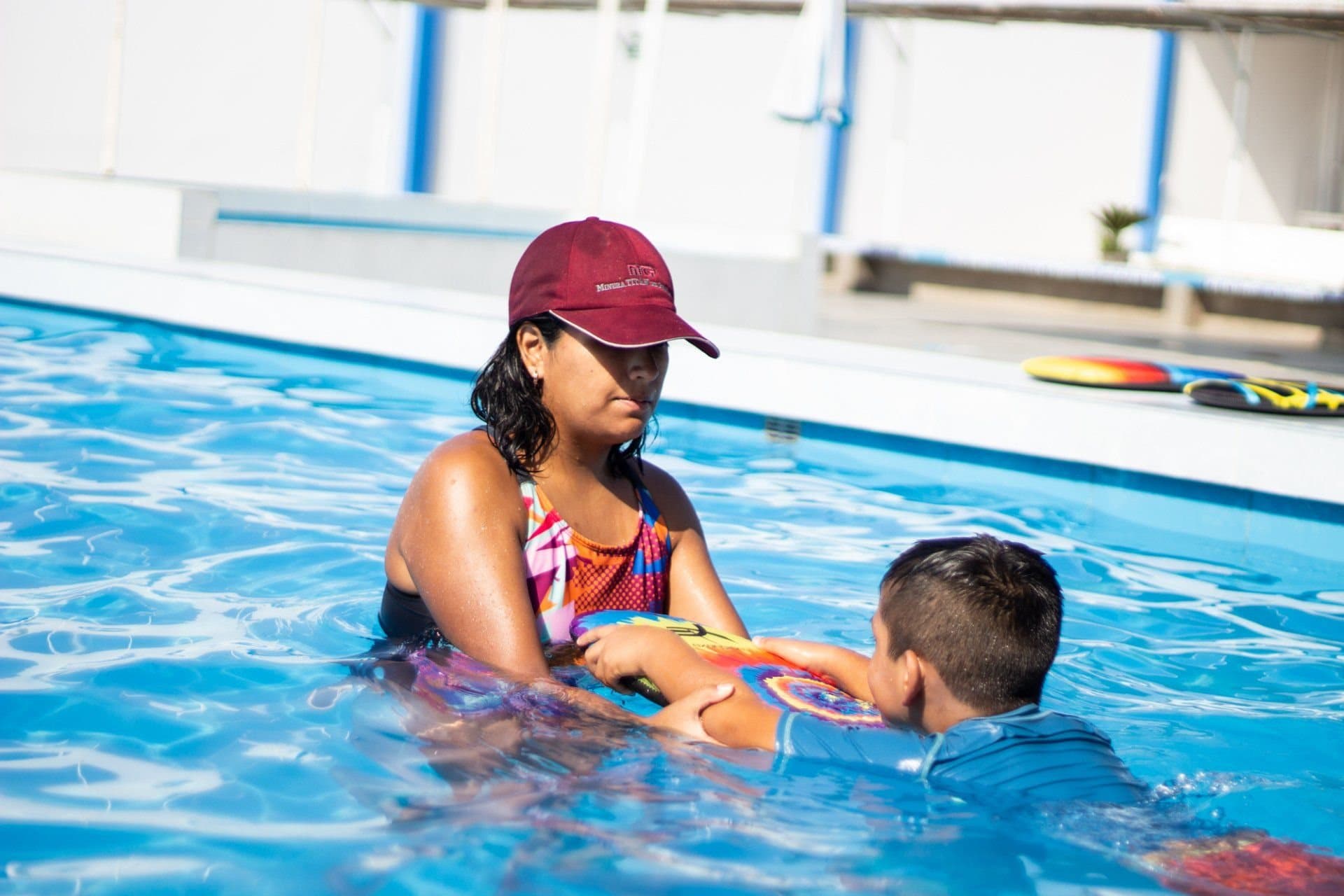 Eine Schwimmlehrkraft unterstützt ein Kind im Becken