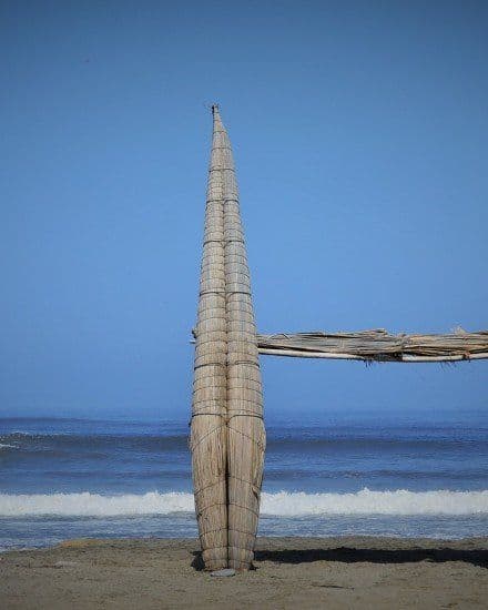 A traditional caballito de totora reed boat standing upright on Huanchaco beach