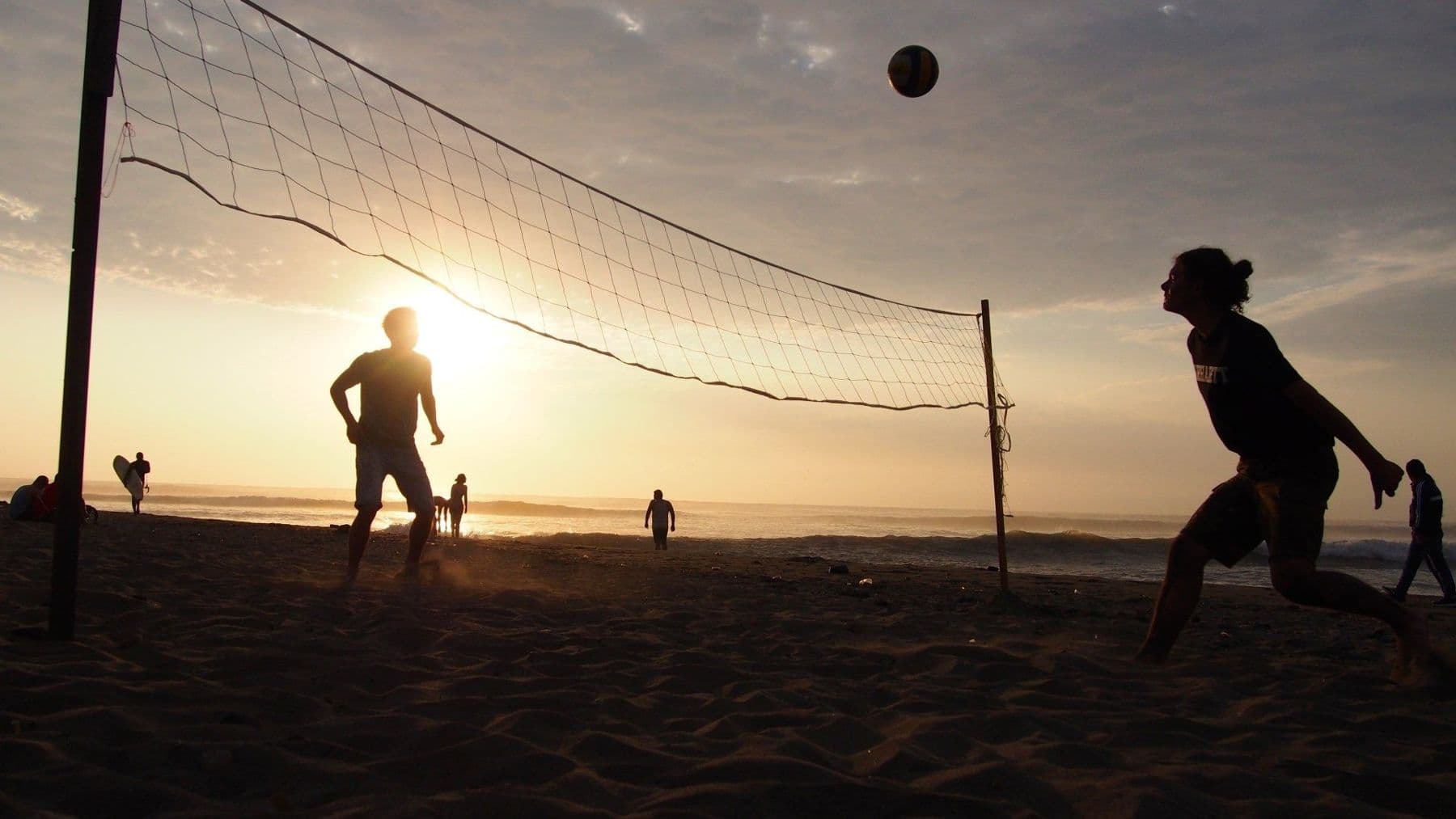 Silhouettes of people playing beach volleyball on Huanchaco beach at sunset