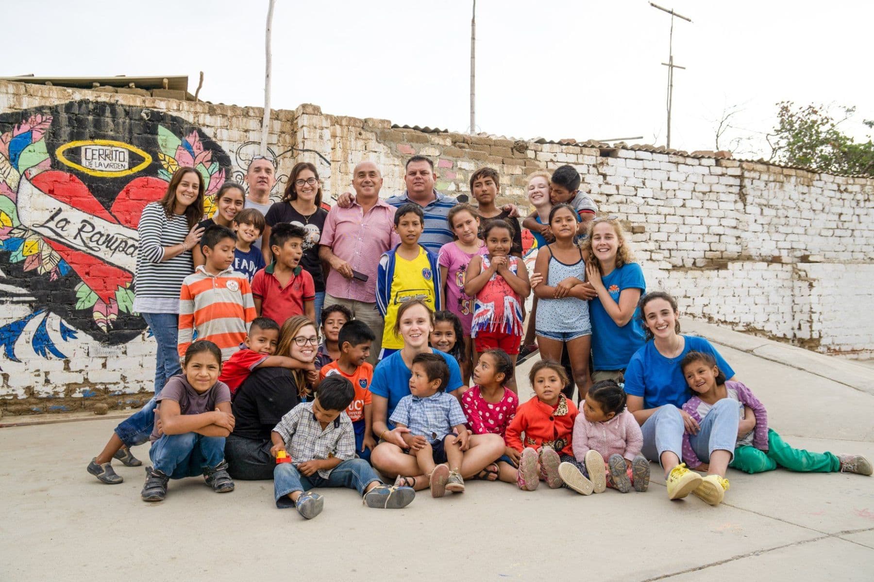 Volunteers, staff and children from Cerrito de la Virgen posing together in front of a painted mural at the skate ramp