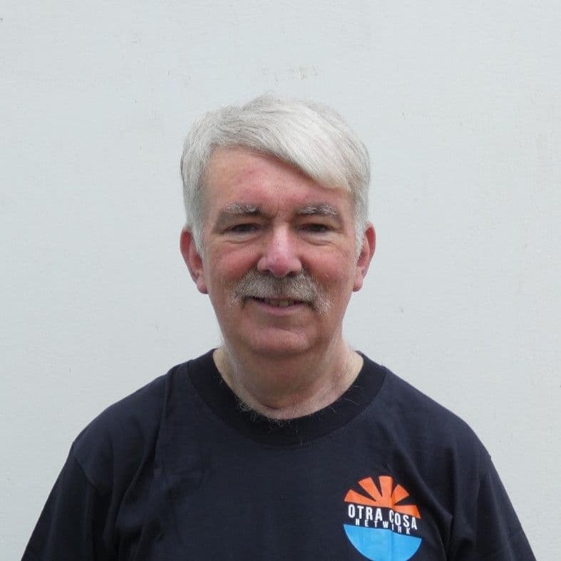 Peter Murphy smiling, wearing a navy Otra Cosa Network T-shirt