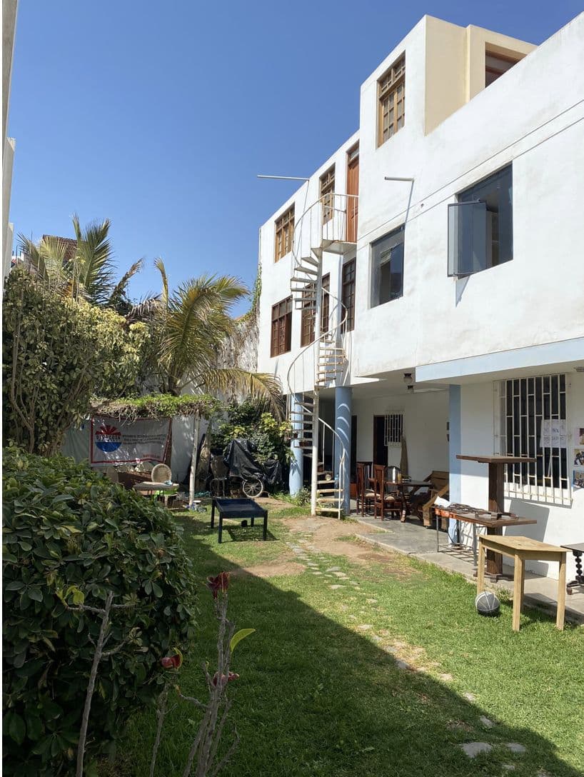 The white OCN volunteer house with palm trees and a lawn