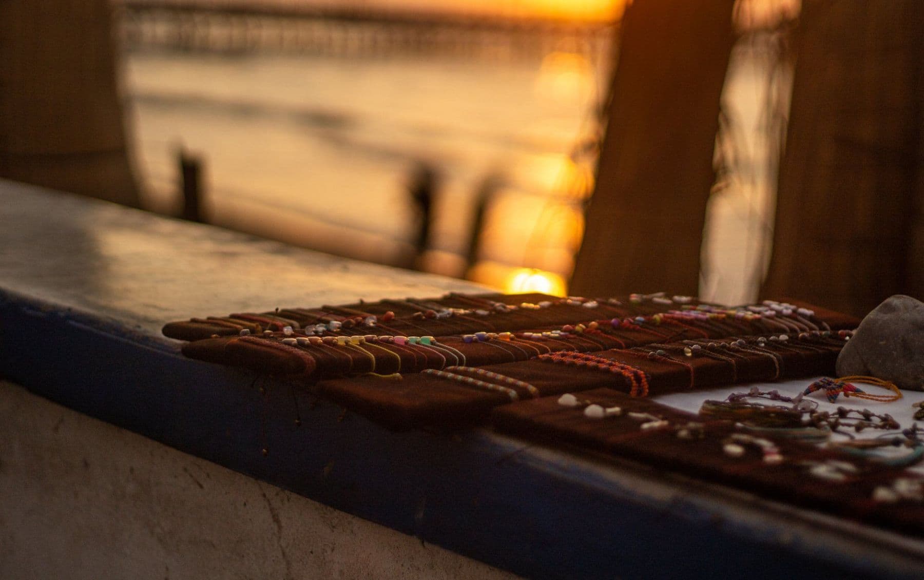 Handmade bracelets laid out on a market stall in the golden evening light